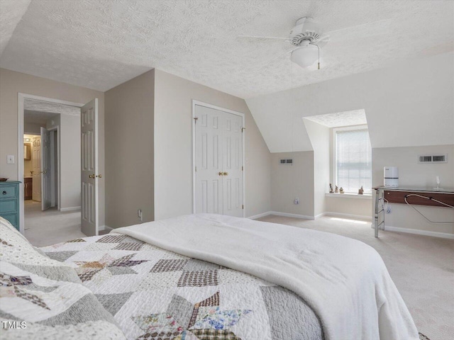 carpeted bedroom with lofted ceiling, a textured ceiling, ceiling fan, and a closet