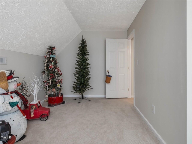 interior space featuring light carpet, vaulted ceiling, and a textured ceiling