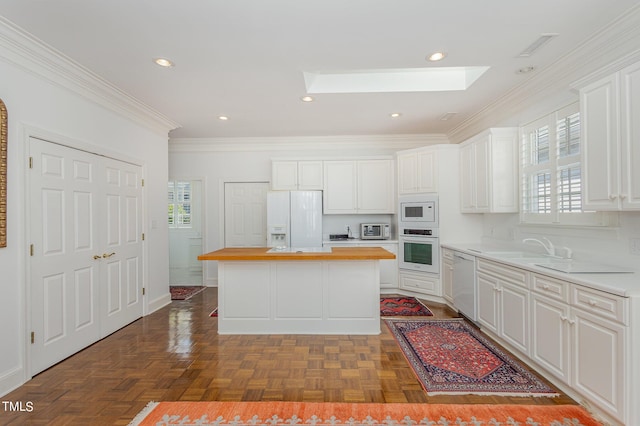 kitchen featuring white appliances, a kitchen island, a skylight, and white cabinets