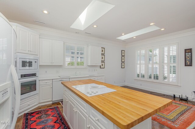 kitchen with butcher block countertops, a center island, white appliances, and a healthy amount of sunlight