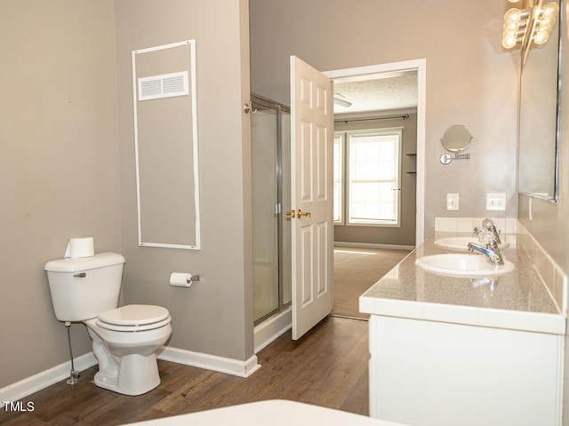 bathroom featuring hardwood / wood-style floors, toilet, a shower with door, and vanity