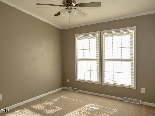 spare room with ceiling fan, a textured ceiling, crown molding, and light carpet