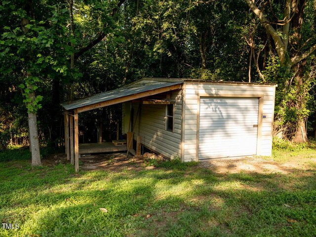 view of outbuilding with a lawn, a carport, and a garage