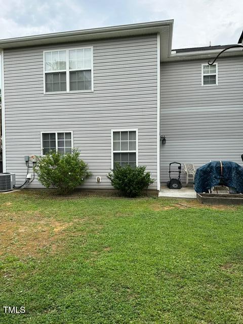 back of house featuring a lawn and central AC unit