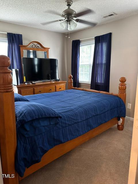 carpeted bedroom featuring ceiling fan and a textured ceiling