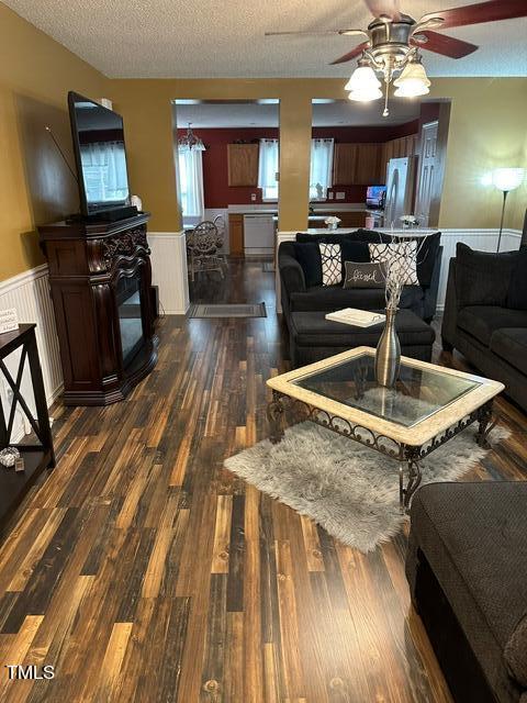 living room featuring dark wood-type flooring, a textured ceiling, and ceiling fan