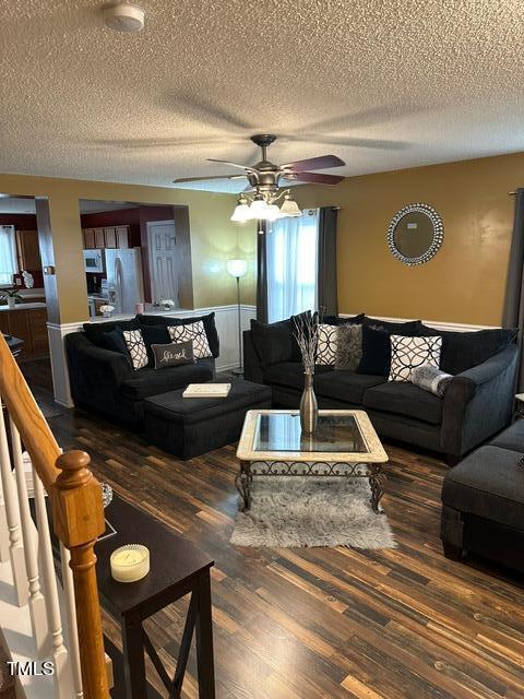 living room with dark hardwood / wood-style flooring, a textured ceiling, and ceiling fan