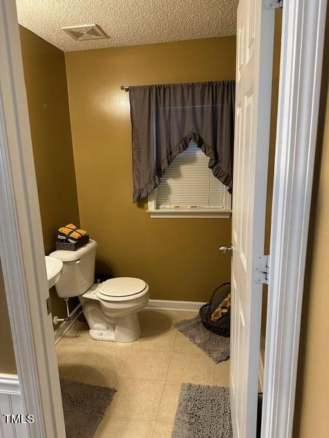 bathroom featuring tile patterned floors, a textured ceiling, and toilet