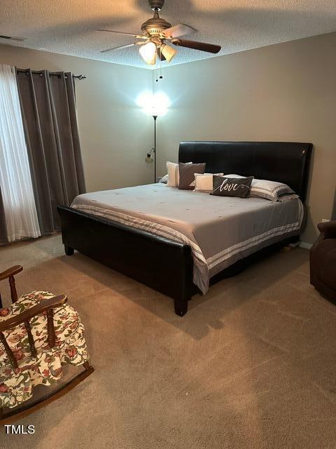 bedroom featuring ceiling fan, carpet, and a textured ceiling