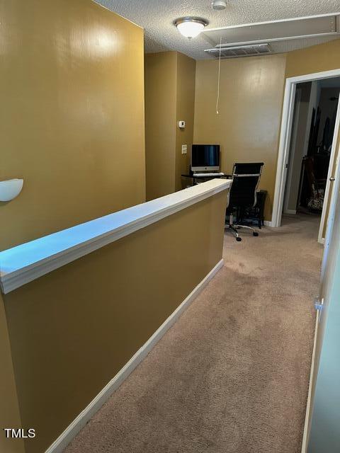 hallway with a textured ceiling and light colored carpet