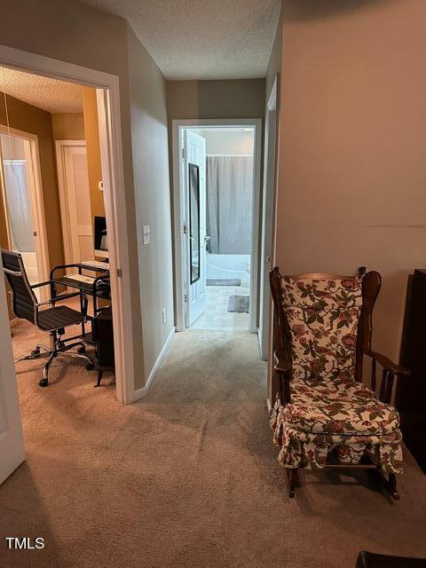 corridor with light carpet and a textured ceiling