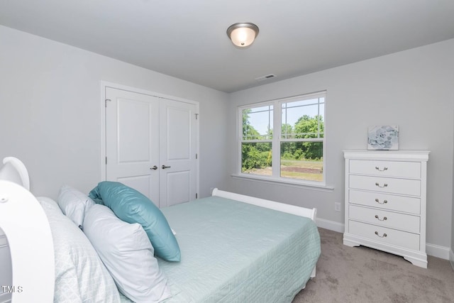 bedroom featuring baseboards, a closet, visible vents, and light colored carpet