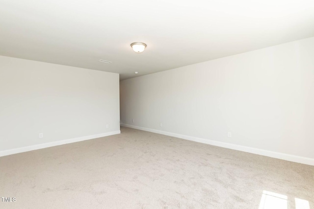 empty room featuring light colored carpet and baseboards