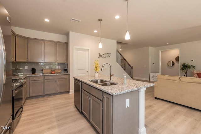 kitchen with stainless steel appliances, light hardwood / wood-style floors, sink, and pendant lighting