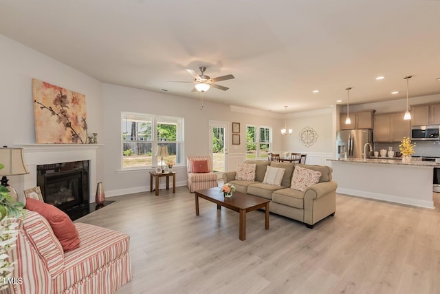 living area with ceiling fan, light wood-type flooring, a fireplace with flush hearth, and recessed lighting