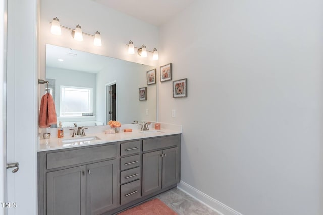 full bathroom featuring double vanity, a sink, and baseboards