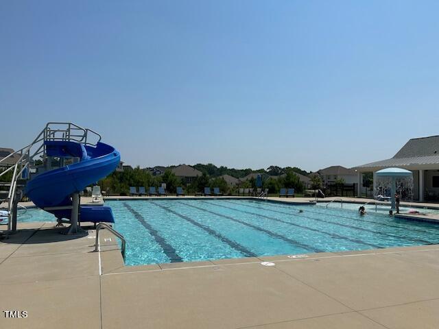 community pool with a water slide and a patio