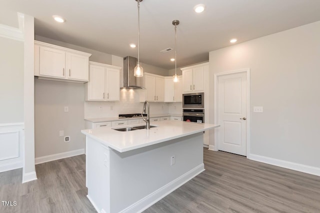 157 Newport Lndg Lot 95, Garner, NC 27529 - kitchen featuring wall chimney exhaust hood, appliances with stainless steel finishes, white cabinets, light wood-style flooring, and light countertops