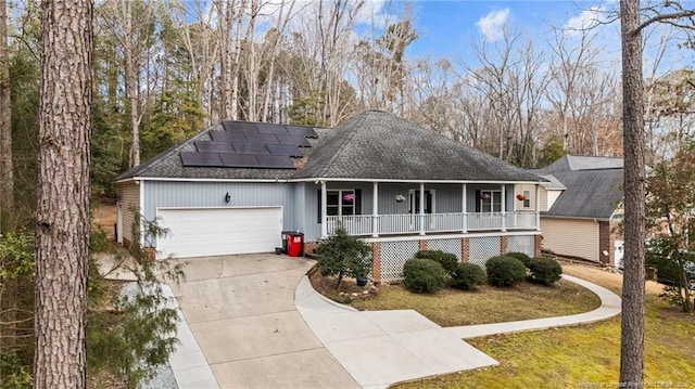 view of front of property with a front yard, solar panels, covered porch, and a garage