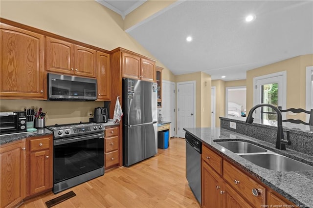 kitchen with sink, light hardwood / wood-style flooring, stainless steel appliances, and dark stone countertops