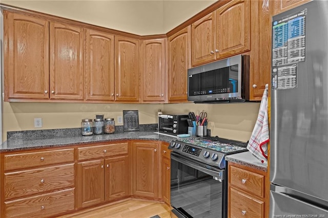 kitchen featuring dark stone countertops, stainless steel appliances, and light hardwood / wood-style floors