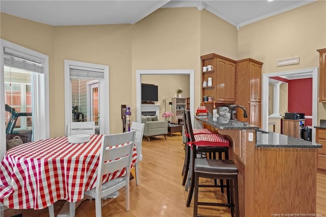 dining area with light hardwood / wood-style floors, sink, and vaulted ceiling