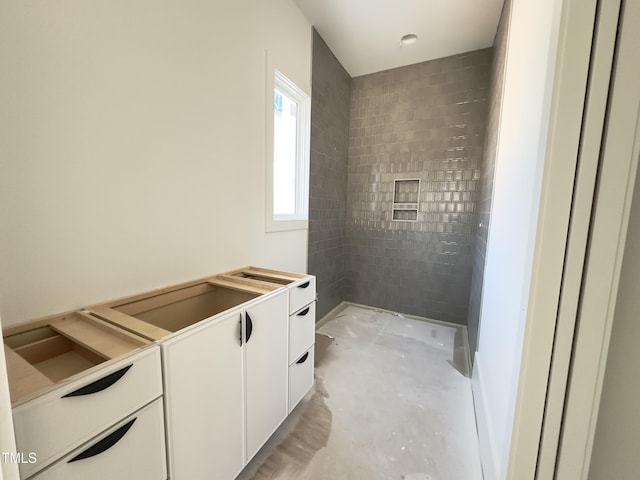 bathroom with concrete floors and a tile shower