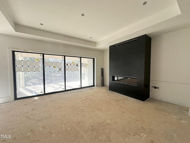 spare room featuring a large fireplace and a raised ceiling