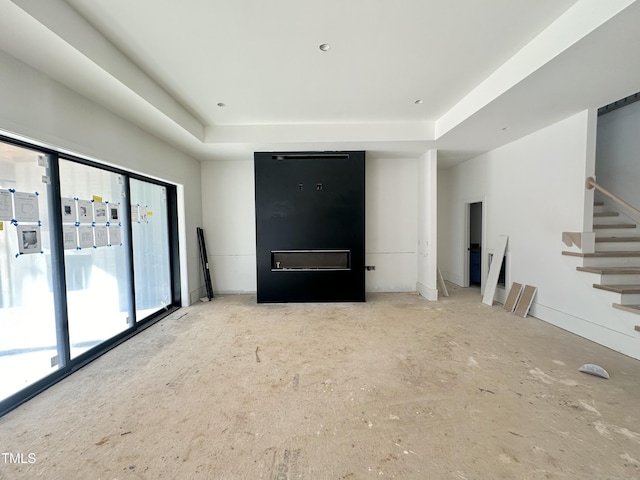 unfurnished living room with stairs and a tray ceiling