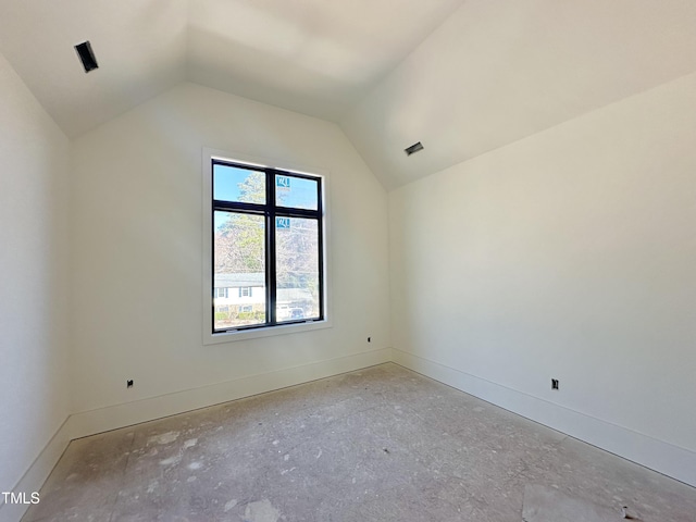 spare room with vaulted ceiling, visible vents, and baseboards