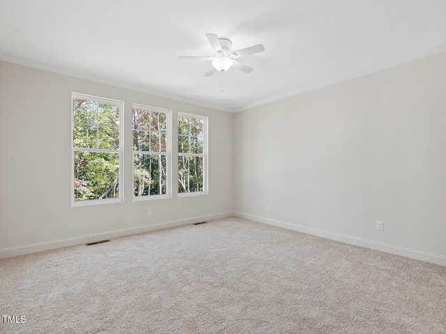 carpeted spare room with crown molding, baseboards, ceiling fan, and visible vents