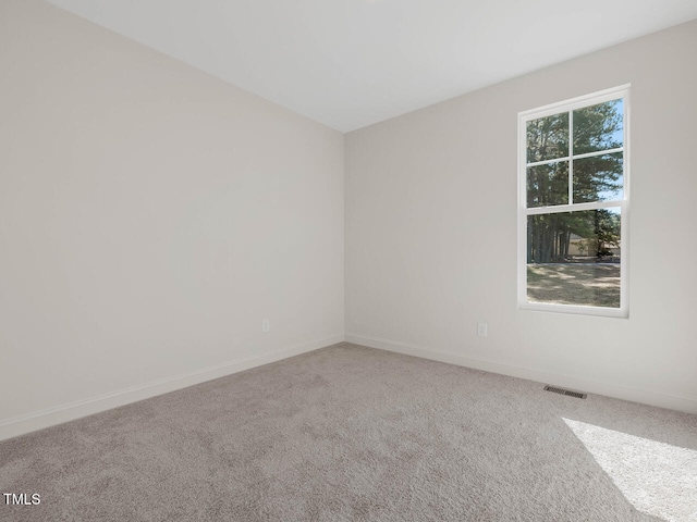 unfurnished room featuring baseboards, visible vents, and carpet
