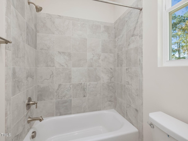 bathroom with toilet and tiled shower / bath