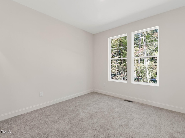 carpeted spare room featuring baseboards and visible vents