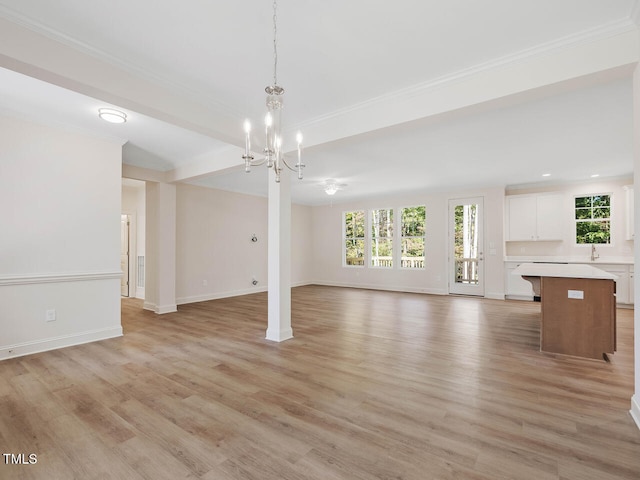 unfurnished living room featuring crown molding, a chandelier, baseboards, and light wood-style flooring