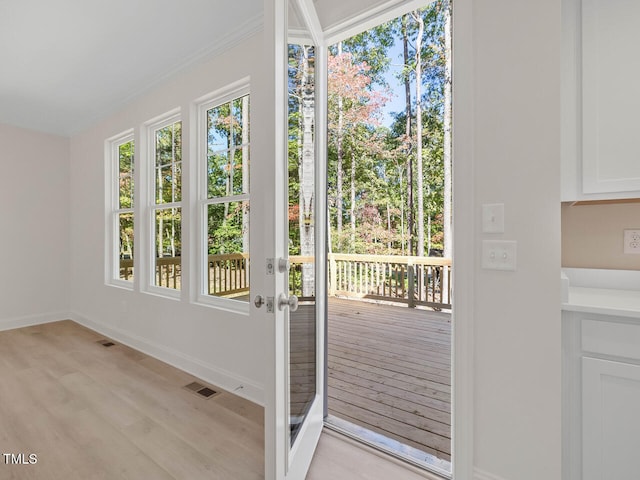 doorway with crown molding and light hardwood / wood-style flooring