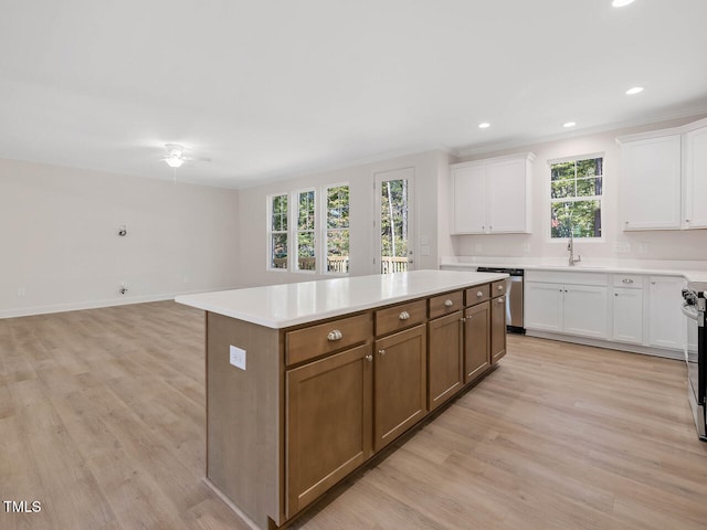 kitchen with a center island, light wood finished floors, light countertops, white cabinets, and appliances with stainless steel finishes