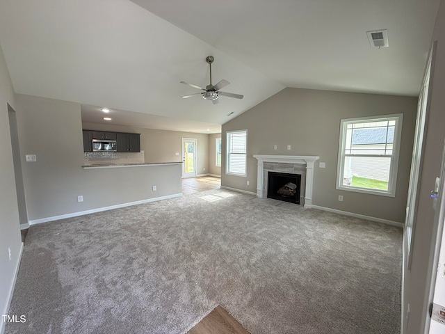 unfurnished living room with dark carpet, lofted ceiling, and a wealth of natural light