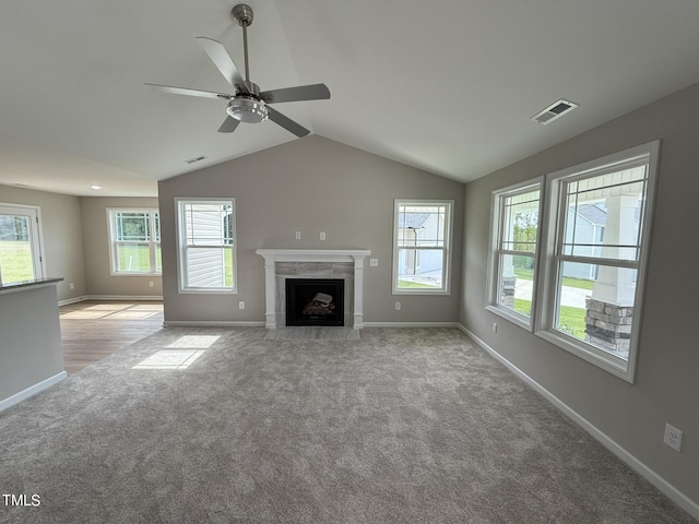 unfurnished living room featuring ceiling fan, light colored carpet, vaulted ceiling, and a healthy amount of sunlight