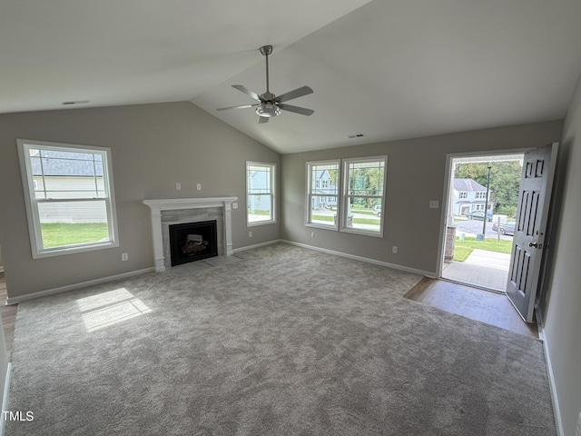 unfurnished living room featuring lofted ceiling, ceiling fan, light colored carpet, and plenty of natural light