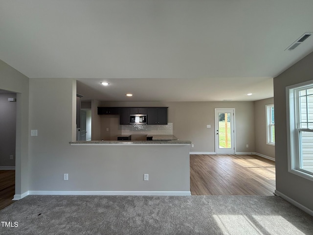 kitchen featuring hardwood / wood-style floors, kitchen peninsula, a healthy amount of sunlight, and backsplash