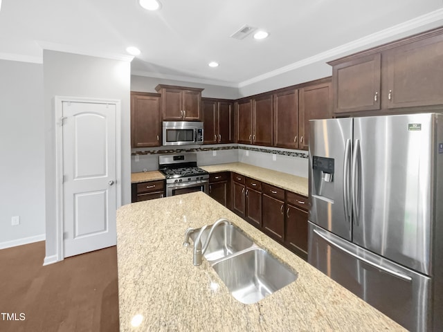 kitchen with appliances with stainless steel finishes, sink, ornamental molding, light stone counters, and dark brown cabinets