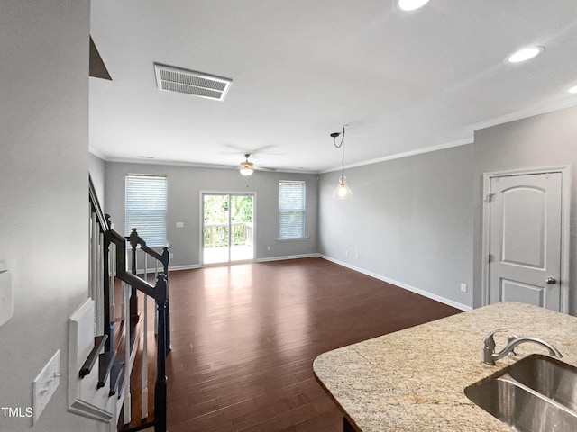 kitchen with sink, crown molding, hanging light fixtures, light stone counters, and dark hardwood / wood-style flooring