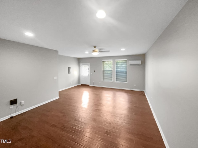 unfurnished room featuring ceiling fan, a wall mounted air conditioner, and dark hardwood / wood-style flooring