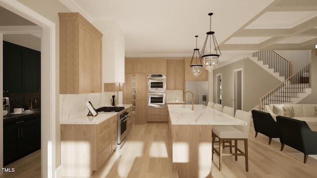 kitchen with tasteful backsplash, appliances with stainless steel finishes, a center island with sink, and light brown cabinets