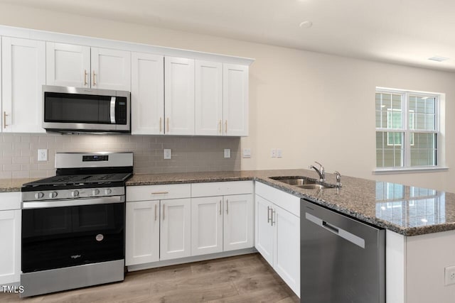 kitchen with sink, white cabinetry, appliances with stainless steel finishes, and kitchen peninsula