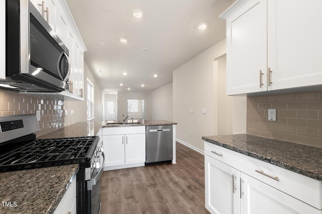 kitchen featuring sink, dark stone countertops, stainless steel appliances, and white cabinetry