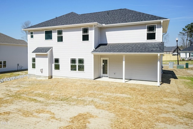 back of property with a patio area and roof with shingles