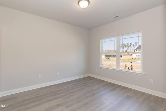 spare room with light wood-style flooring, visible vents, and baseboards