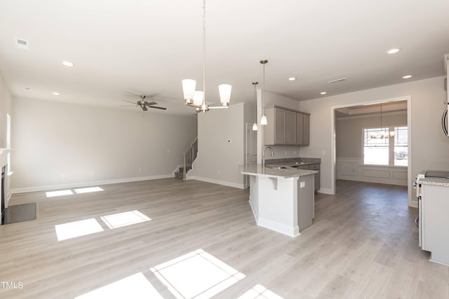 kitchen featuring gray cabinets, open floor plan, pendant lighting, and a kitchen breakfast bar